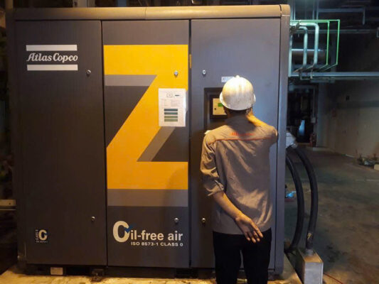 Kỹ thuật viên kiểm tra bộ điều khiển Elektronikon trên máy nén khí Atlas Copco VSD không dầu.