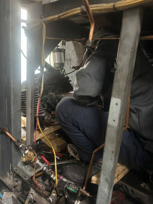 Thợ sửa máy nén khí len lỏi vào vị trí hẹp để bảo trì hệ thống khí nén ở phố cổ Hoàn Kiếm.