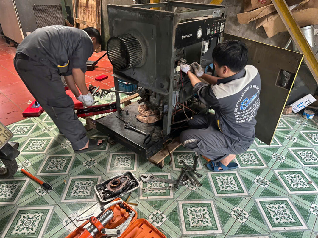 Kỹ thuật viên sửa chữa máy nén khí Hitachi Nhật bãi lỗi bảng điều khiển tại xưởng Việt Nhật
